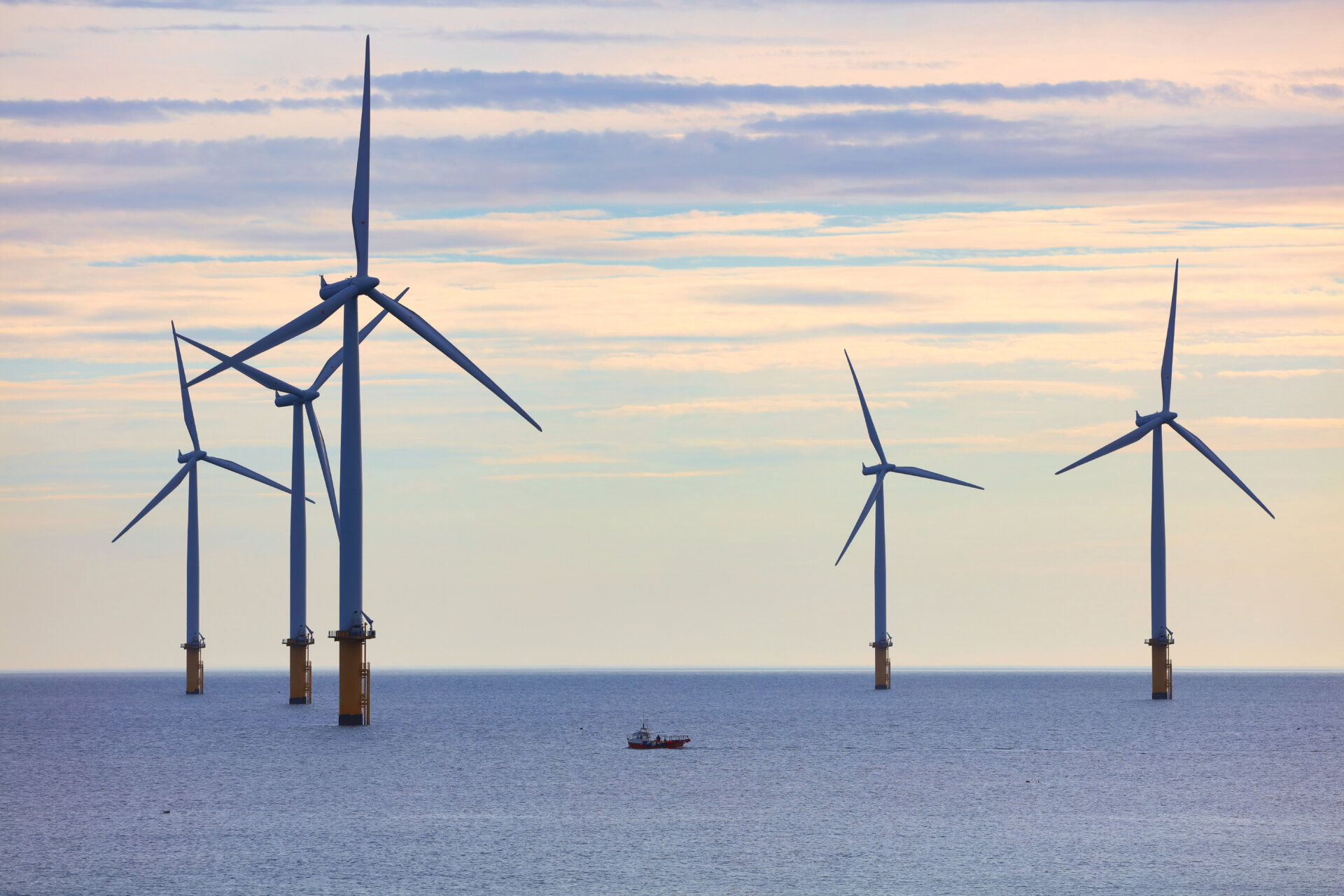 Small Fishing Boat dwarfed by huge Wind Turbines off the North East Coast, Redcar, North Yorkshire, England, UK.