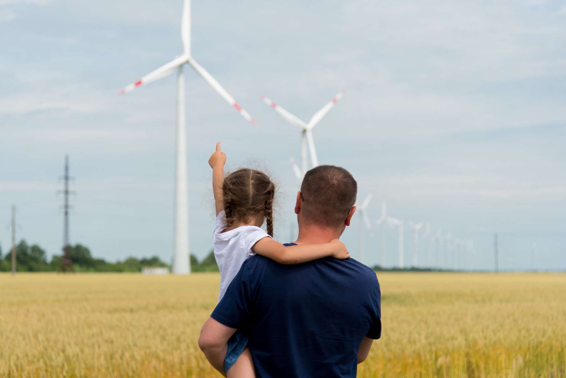 A girl and her dad look at the wind generator in the field. Ecology. Future.