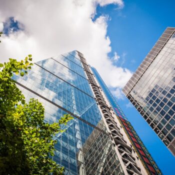 Financial glass buildings in the City of London with a green tree on the left