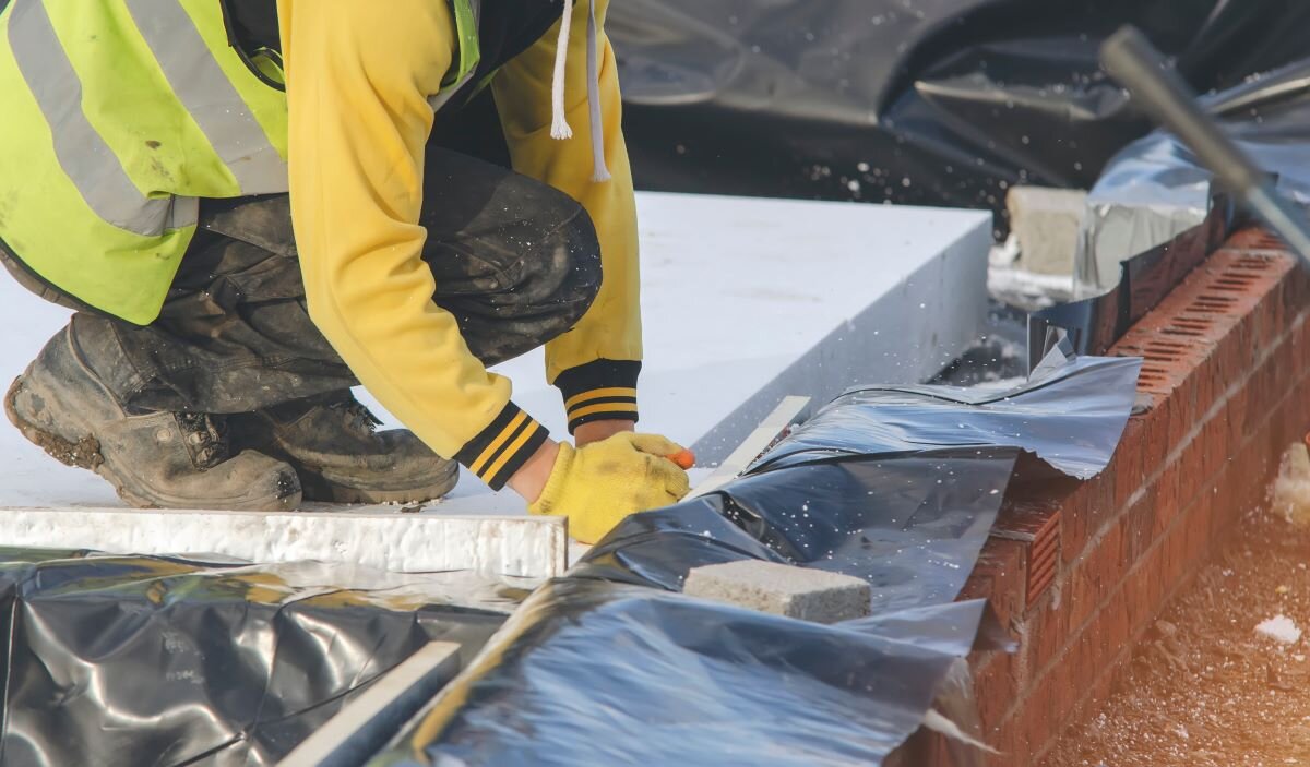 An installer fits insulation in a UK home. Housing constitutes 14% of UK emissions, largely from heating, and there is little prospect of hitting climate goals if these are not substantially cut.